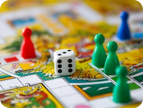 Grande plano de um jogo de tabuleiro colorido com peças de madeira, um dado e um tabuleiro detalhado, ideal para diversão em família e jogos de mesa.